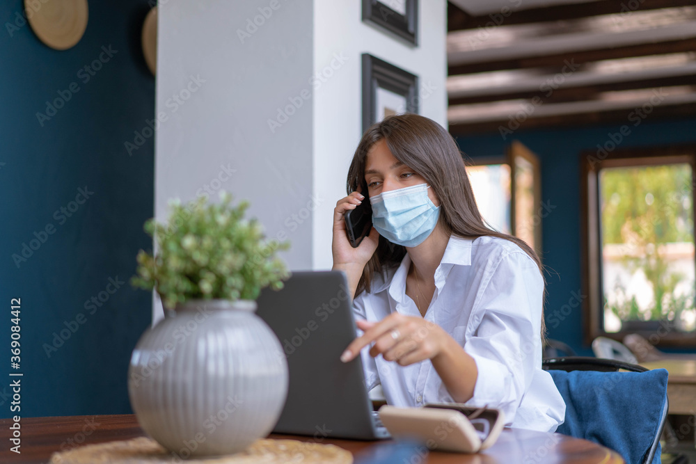 Young beautiful woman wearing protective face mask and working on laptop computer. Young beautiful woman wearing protective face mask and working on laptop computer.