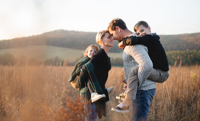 Beautiful young family with small children on a walk in autumn nature.