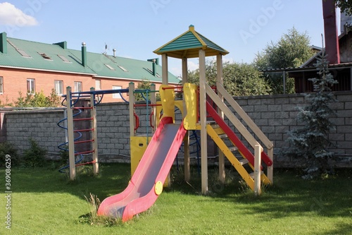 Playground in the yard of an apartment building on the street with slides, stairs, with swings