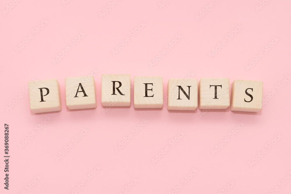 The word PARENTS is made of wooden cubes on a pink background. The word PARENTS is made of wooden cubes on a pink background.