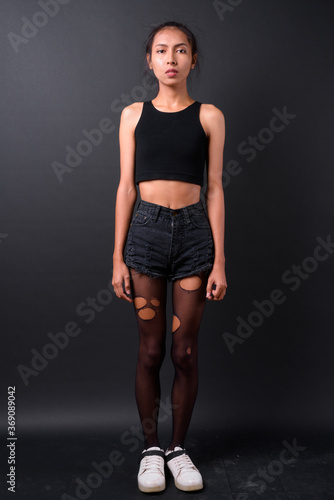 Young beautiful Asian transgender woman against black background © Ranta Images