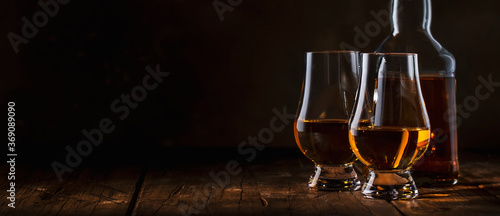 Fotografiet Scotch Whiskey without ice in glasses and bottle, rustic wood background, copy s