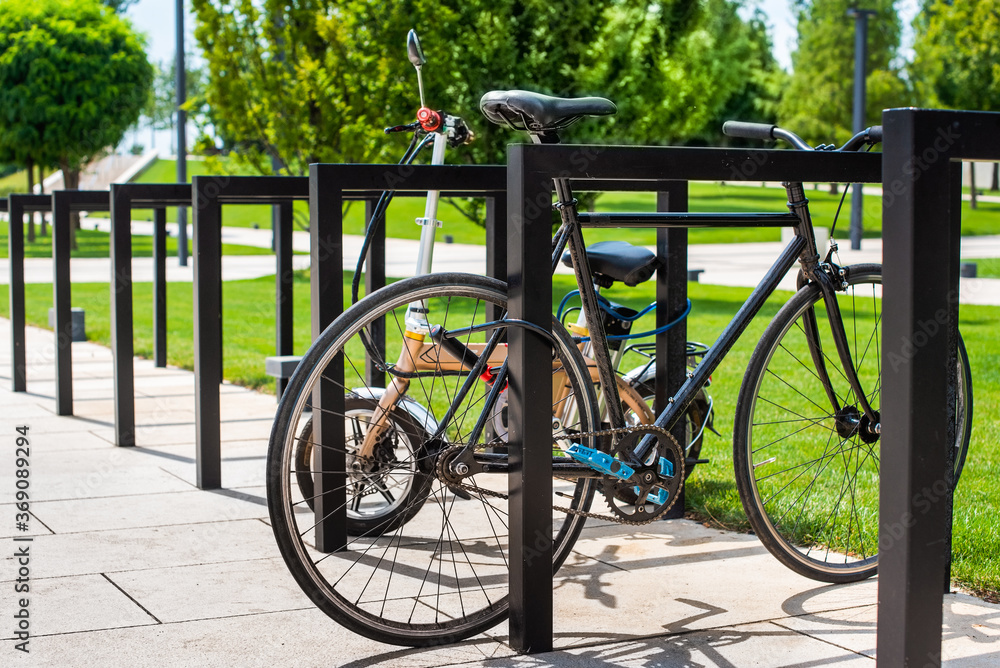 a bicycle and an electric scooter are in the parking lot. fastened with a padlock. bicycles are not allowed in the park a bicycle and an electric scooter are in the parking lot. fastened with a padlock. bicycles are not allowed in the park