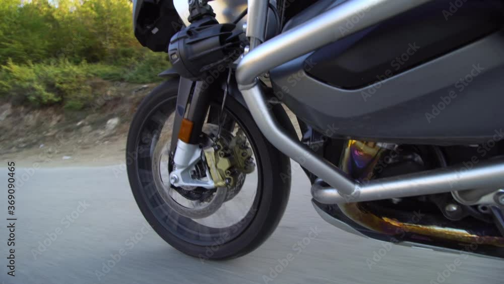 Motorcycle ridind on a road in nature. Close up wheel on a bumpy asphalt road. Motorcycle ridind on a road in nature. Close up wheel on a bumpy asphalt road.