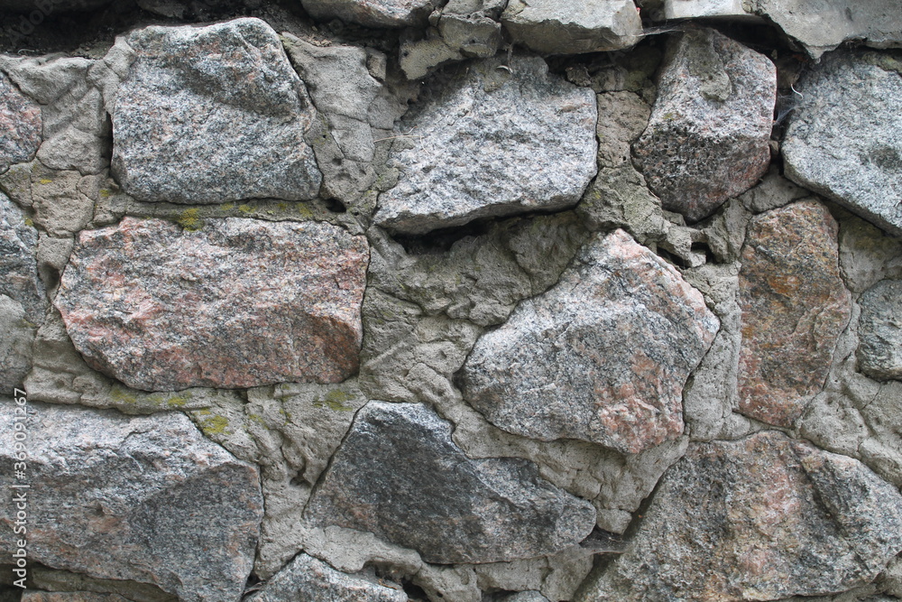 Masonry. A wall of rough large stones. Concrete seams. Old building Masonry. A wall of rough large stones. Concrete seams. Old building