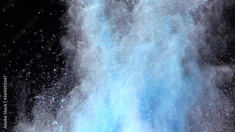 Super slow motion explosion of colorful blue powder on dark isolated background. Lumps of powder fly upwards and mix with the smoke. Super slow motion explosion of colorful blue powder on dark isolated background. Lumps of powder fly upwards and mix with the smoke.