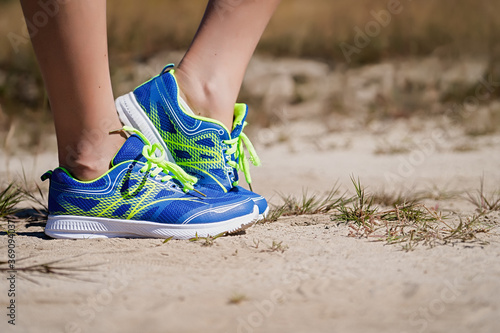 Close up view of a young woman standing on a natural dirt road in sports shoes getting ready to run and exercise