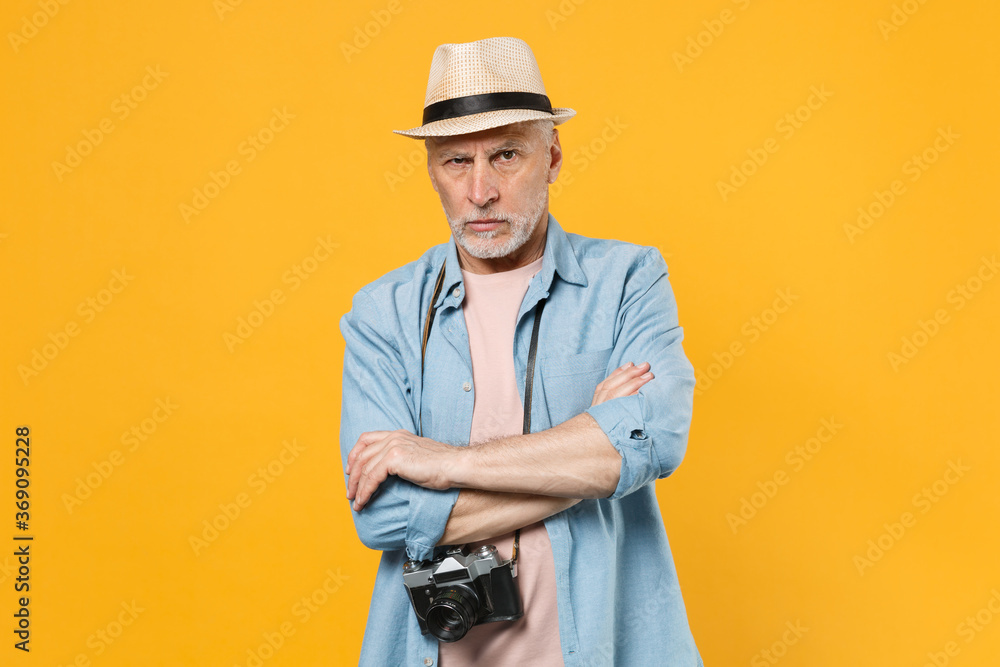 Perplexed traveler tourist elderly gray-haired man in hat photo camera isolated on yellow background. Passenger traveling abroad on weekend getaway. Air flight journey concept. Holding hands crossed. Perplexed traveler tourist elderly gray-haired man in hat photo camera isolated on yellow background. Passenger traveling abroad on weekend getaway. Air flight journey concept. Holding hands crossed.