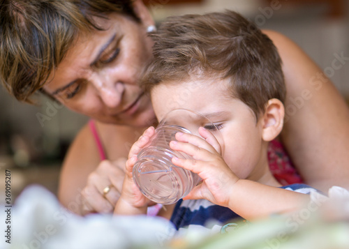 Little boy eating with his grandmother in the kitchen photo