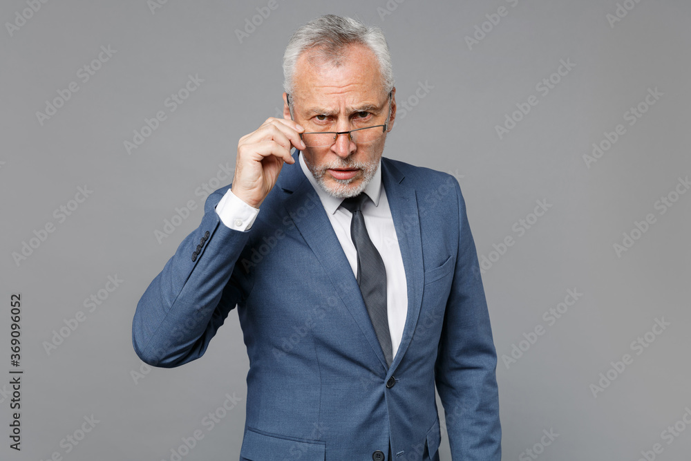 Perplexed elderly gray-haired mustache bearded business man in classic blue suit shirt tie isolated on grey wall background studio portrait. Achievement career wealth business concept. Looking camera. Perplexed elderly gray-haired mustache bearded business man in classic blue suit shirt tie isolated on grey wall background studio portrait. Achievement career wealth business concept. Looking camera.
