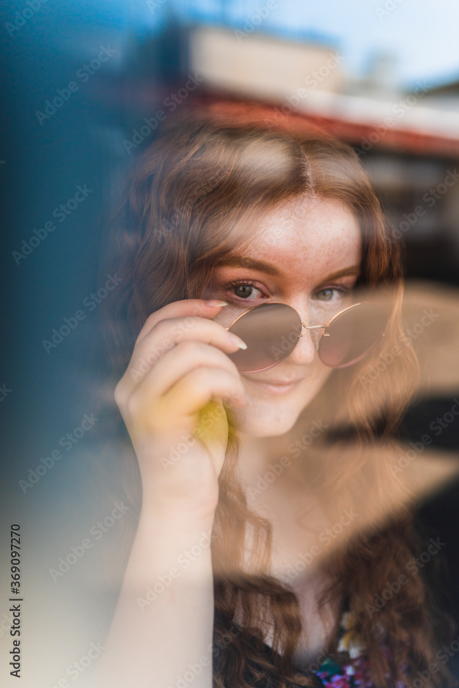 Red hair woman behind a closed window taking off her sunglasses Red hair woman behind a closed window taking off her sunglasses