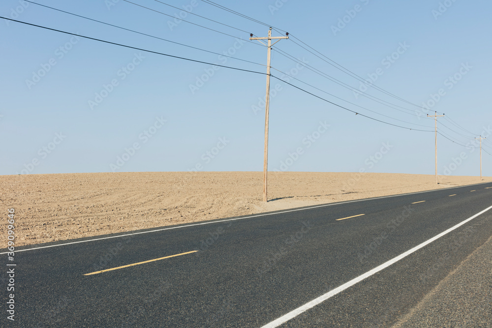Road through fallow fields in summer, telephone poles in distance Road through fallow fields in summer, telephone poles in distance