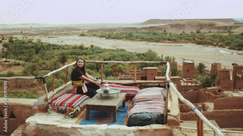 Wallpaper Mural Pretty woman sitting on a rooftop terrace with a beautiful view of the ruins of an abandoned city The famous Ait Benhaddou Kasbah, old town, Beautiful touristic places of Morocco, full hd Torontodigital.ca