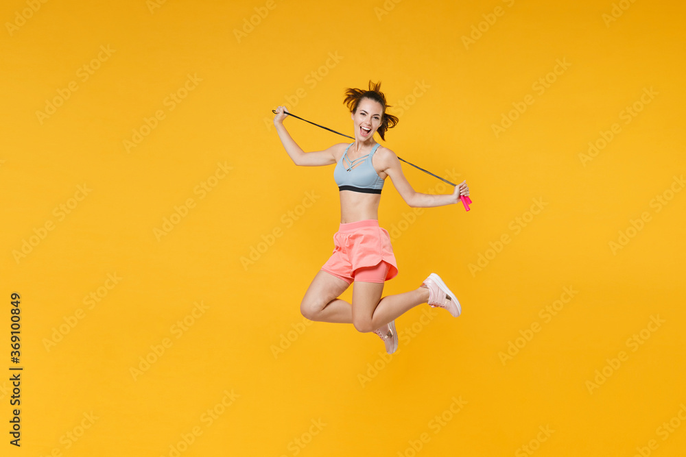 Full length portrait excited young fitness woman in sportswear working out isolated on yellow background. Workout sport motivation lifestyle concept. Mock up copy space. Jumping, hold skipping rope. Full length portrait excited young fitness woman in sportswear working out isolated on yellow background. Workout sport motivation lifestyle concept. Mock up copy space. Jumping, hold skipping rope.