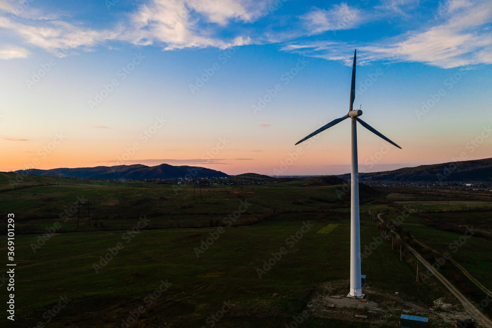 Fototapeta premium One windmill in the field, production of environmentally friendly energy, the beginning of wind energy production in Ukraine, a windmill against the backdrop of the sunset.