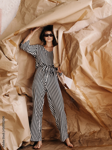 Artistic woman in sunglasses tearing craft caper off wall