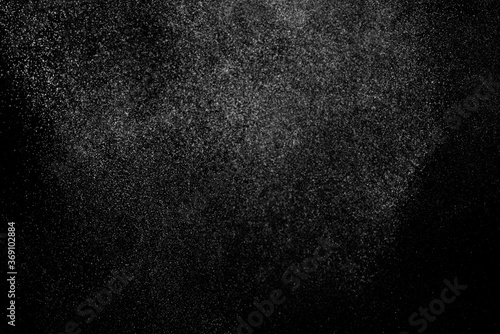 Abstract splashes of water on black background. Freeze motion of white particles. Rain, snow overlay texture.