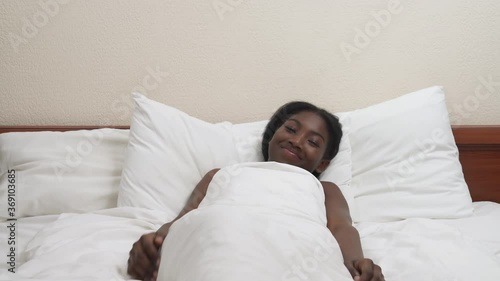 Focus on black man's hands unpacking condom. In the background lying on bed woman in anticipation of intercourse. Bokeh effect. Safe sexual life concept