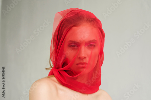 Beauty portrait of a girl covered by red veil