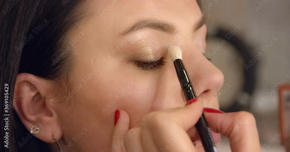 Makeup artist applies eye shadows to the upper eyelid of the model eyes. Makeup artist applies eye shadows to the upper eyelid of the model eyes.