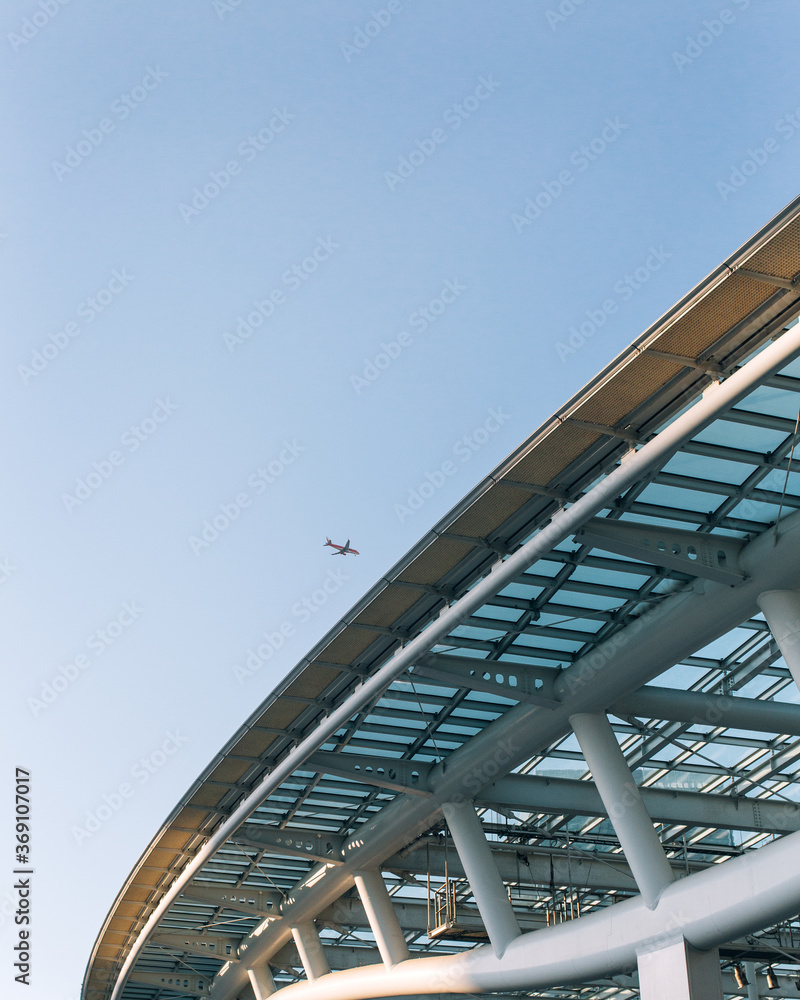 Airplane against a blue sky and about to fly over a steel structure in the city. Airplane against a blue sky and about to fly over a steel structure in the city.