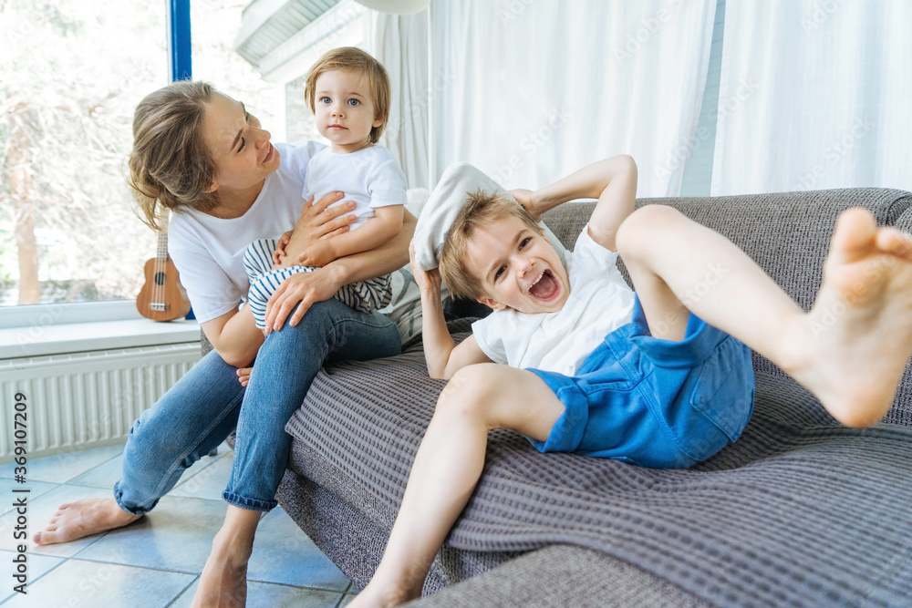 Joyful mother having fun with kids on sofa Joyful mother having fun with kids on sofa