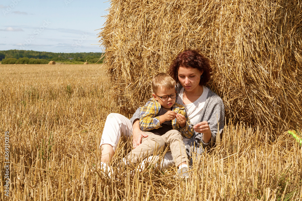 Mother and son relaxing near hay roll Mother and son relaxing near hay roll