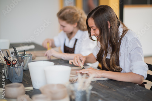 Beautiful young female artist girls creating handmade pottery in modern art studio. Education kids and parents.