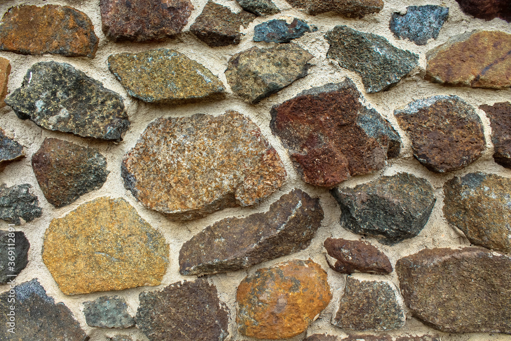 Background image of a textured multicolored stone wall 