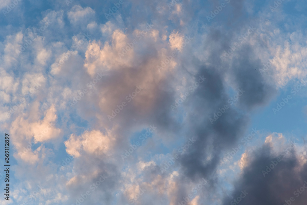 Fototapeta premium Cloudscape: cloudy sunset sky. Grey and white clouds over a bright blue sky