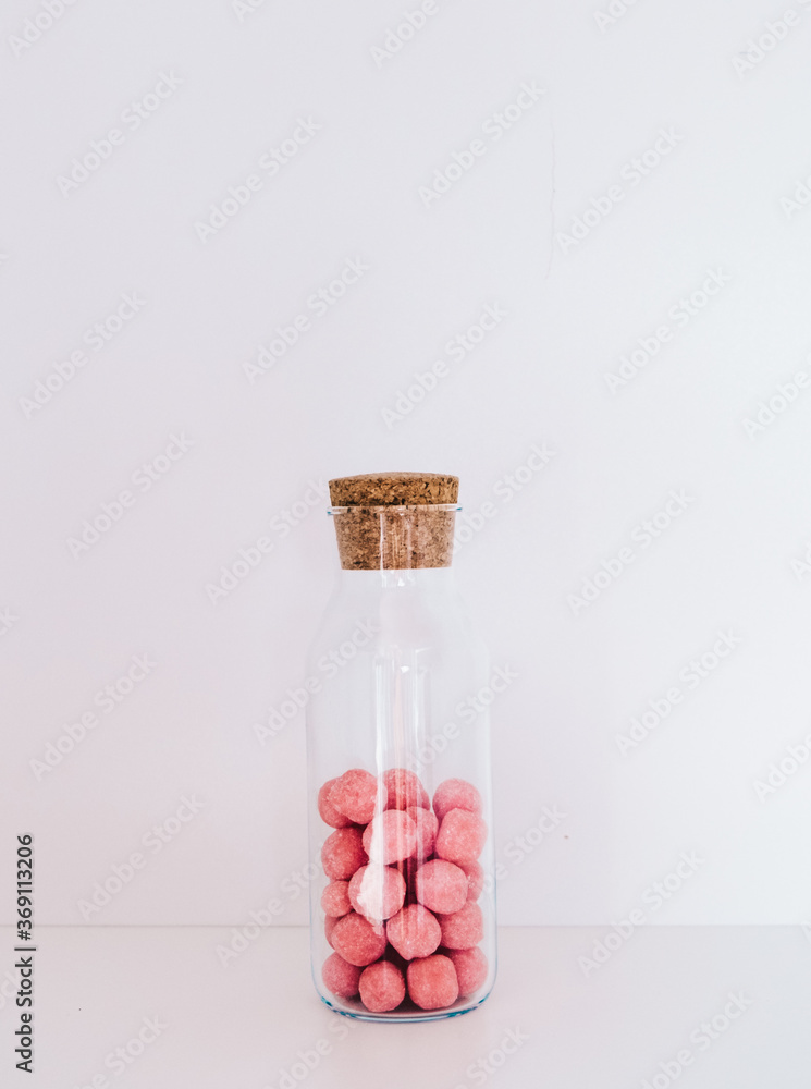 Glass jar on a white background with pink candies inside Glass jar on a white background with pink candies inside