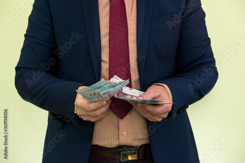 A man in a suit holds a large pile of Ukrainian money and shows his income.  new banknotes 1000 and 500 hryvnia