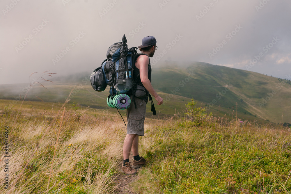 photo of a guy in camping equipment on a background of clouds and mountain peaks photo of a guy in camping equipment on a background of clouds and mountain peaks