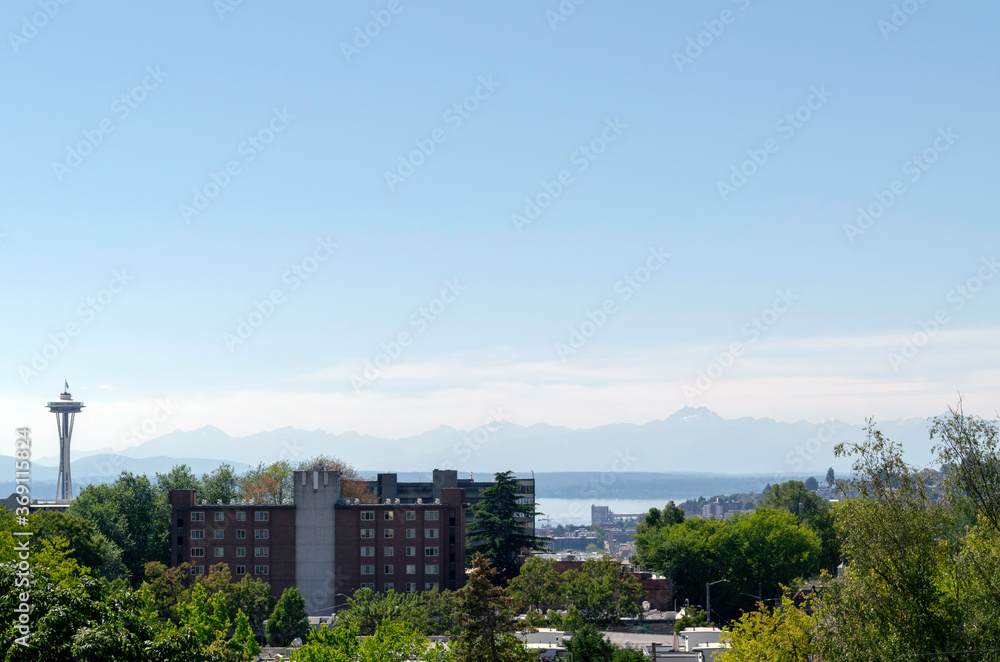 Panoramic view of the Olympic Mountain Range across from Seattle and partial view of a Seattle neighborhood with Space Needle on the left.