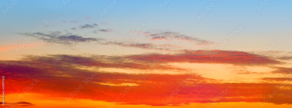 Obraz premium orange sunset sky panorama landscape background. Panoramic cloudscape at dusk. Mellow sunrise ultra wide view. Natural color of summer evening nature with sun below horizon