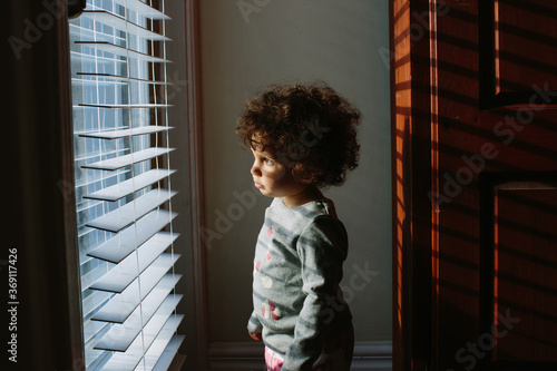 Kid looking through window blinds photo