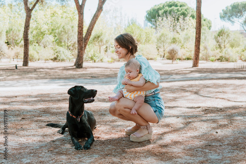 Happy mother with cute baby and dog in park