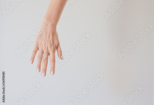  Female hand with a beautiful manicure on a background of a white wall. Delicate and healthy skin on the hands, rejuvenation of the skin of the hands, moisturizing and care