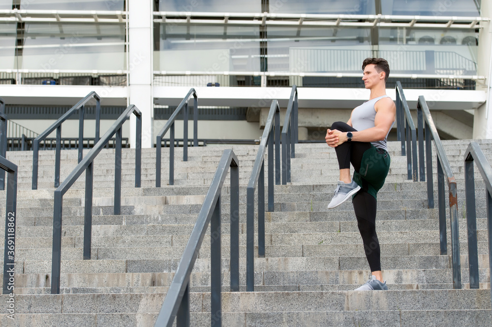 Keeping those muscles flexible. Young male runner athlete training and exercising outdoors in the city. Warm up firstly. Concentrated strong man stretching his leg. Having a good stretch Keeping those muscles flexible. Young male runner athlete training and exercising outdoors in the city. Warm up firstly. Concentrated strong man stretching his leg. Having a good stretch