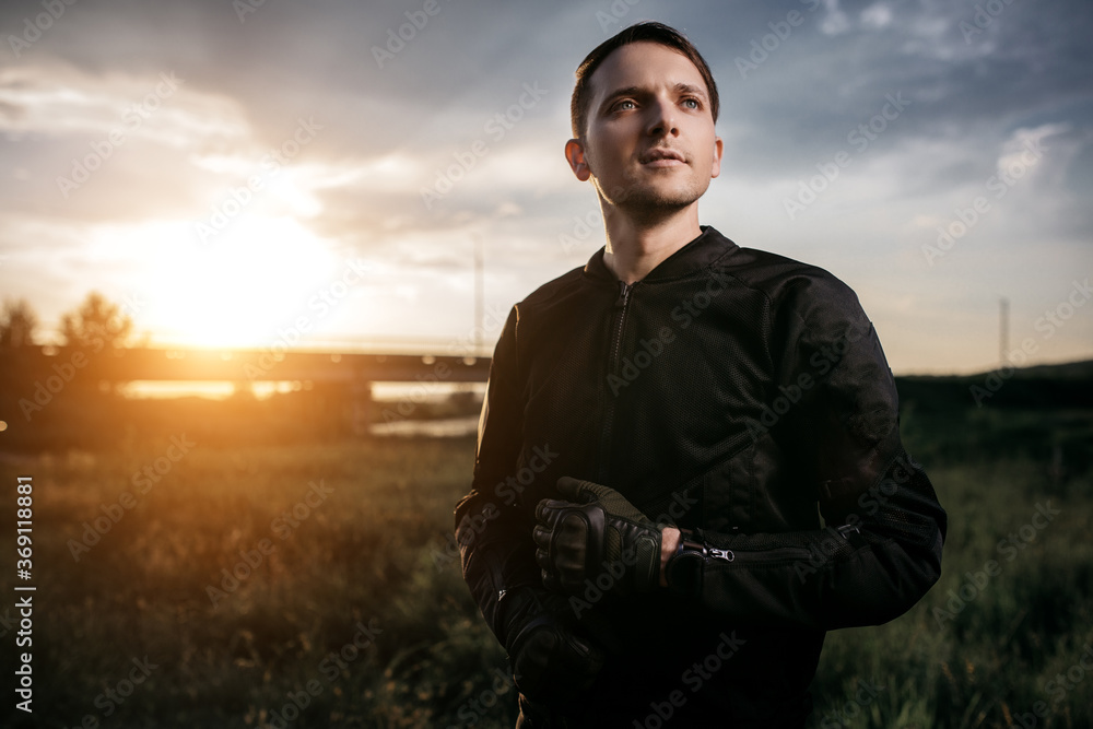Portrait of handsome biker in sunset on the country road. Portrait of handsome biker in sunset on the country road.
