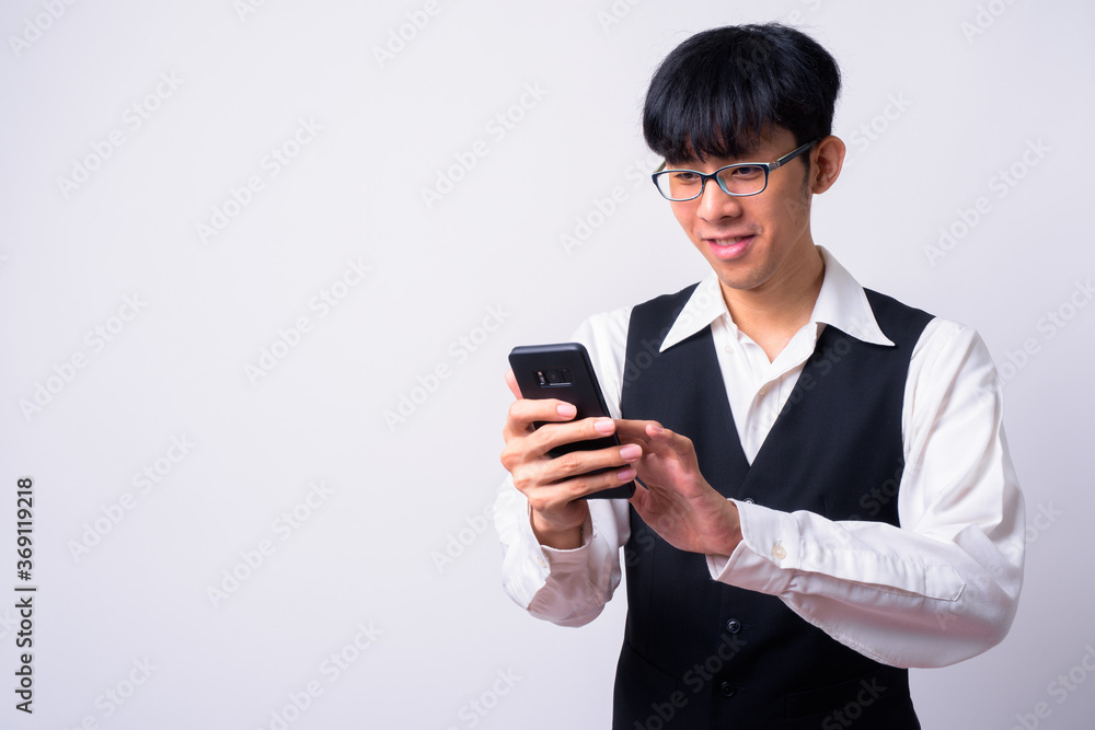 Portrait of happy young handsome Asian businessman using phone Portrait of happy young handsome Asian businessman using phone