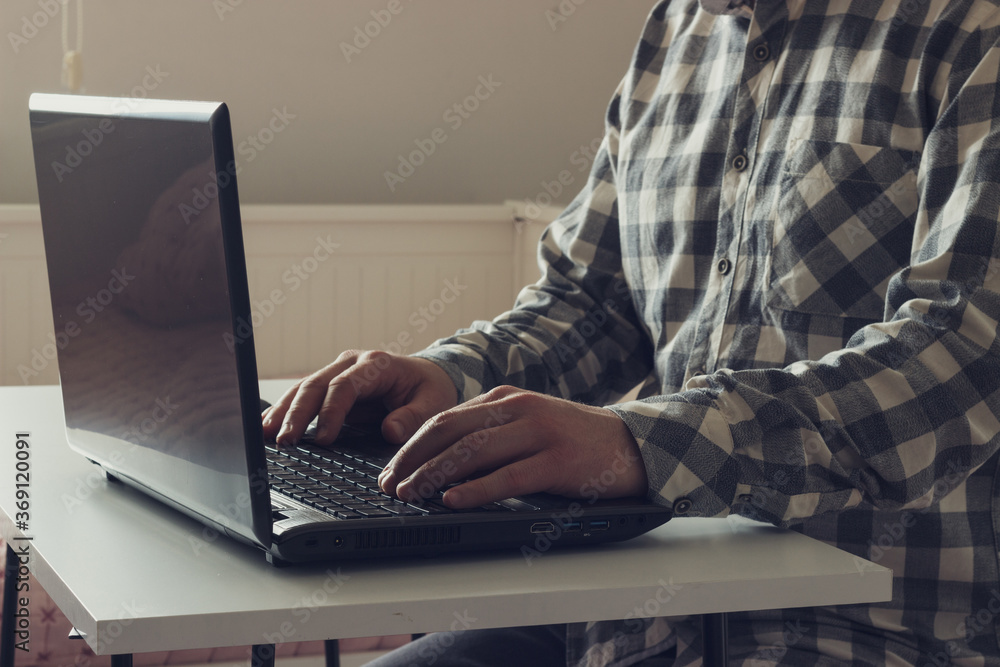 Fototapeta premium Caucasian young man is working with notebook in home. Man is typing on computer. Freelance work concept. Retro style.