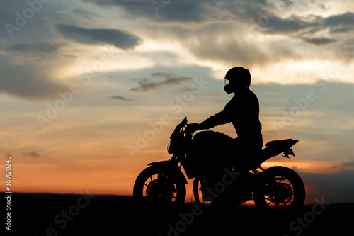 Silhouette photo of biker driving motorcycle in sunset on the on country road. © Screaghin