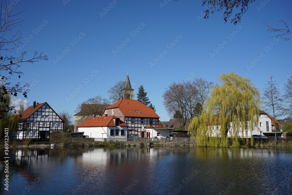 Spiegelung von Häusern im Wasser an einem Teich in einem Ort