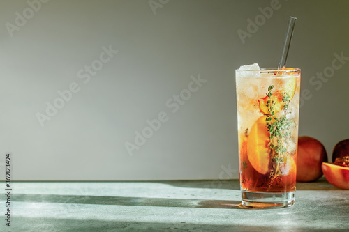Foto Refreshing peach iced tea Cuba Libre or Long Island iced tea cocktail in glass with straw