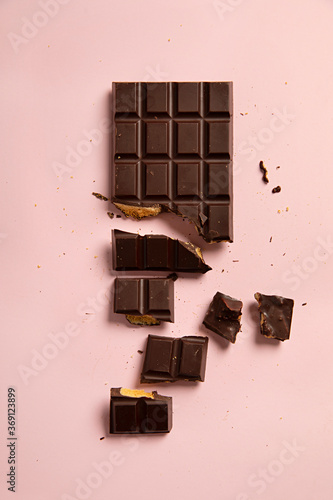 Block of dark chocolate and honeycomb on pink background photo