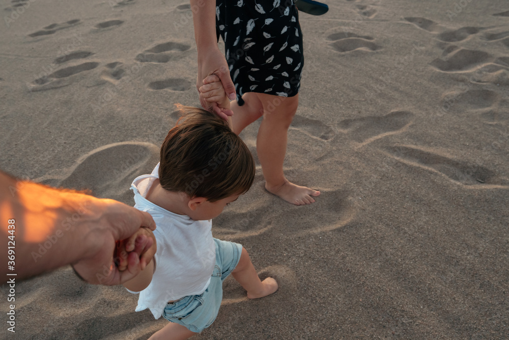 Crop parents walking with toddler on beach Crop parents walking with toddler on beach