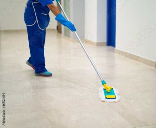 A cleaning lady cleans the hallway with a mop photo