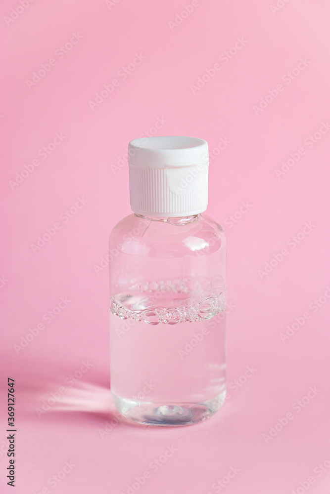 Bottle with micellar cleansing water on pink background. Skin care concept. Bottle with micellar cleansing water on pink background. Skin care concept.