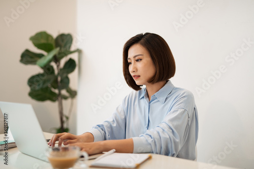 Serious beautiful woman looking at open laptop computer on table photo